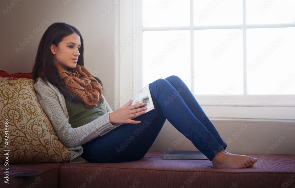 Reading an interesting article. A young woman reading a book at home.