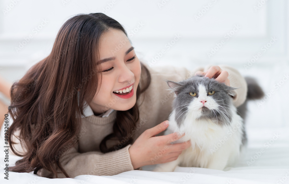 年轻的亚洲女人在家里玩猫