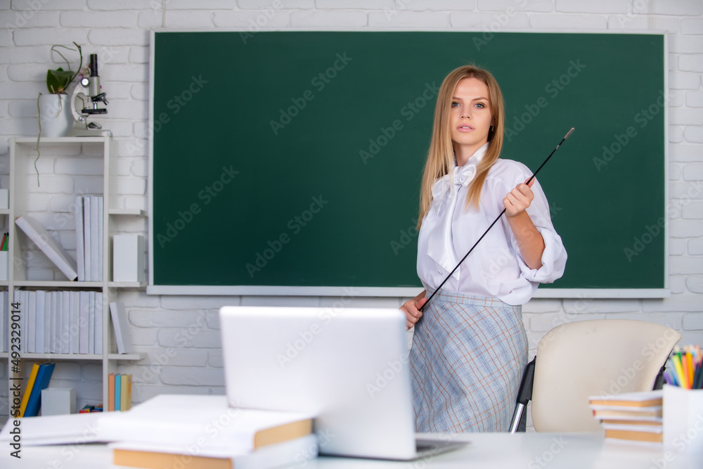 Young teacher with pointer on blackboard with copy space. Portrait of a young, confident and attract