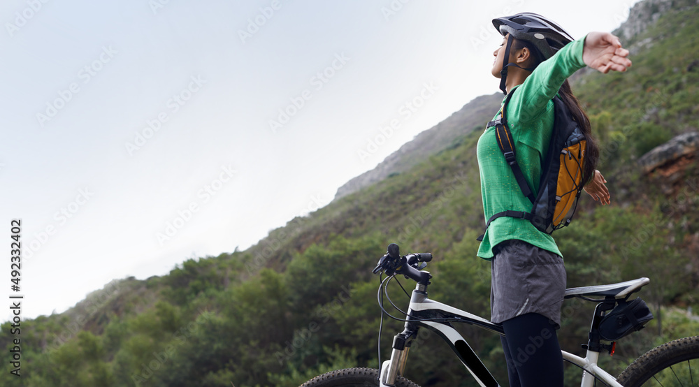 I feel so free. A pretty young woman mountain biking in a scenic setting.