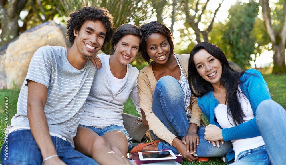 College diversity. Shot of a diverse group of college students sitting outside using digital tablet.