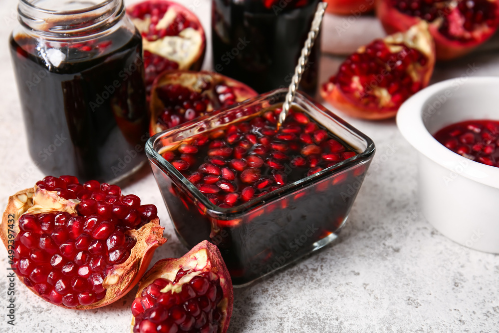 Bowl of pomegranate molasses on light background