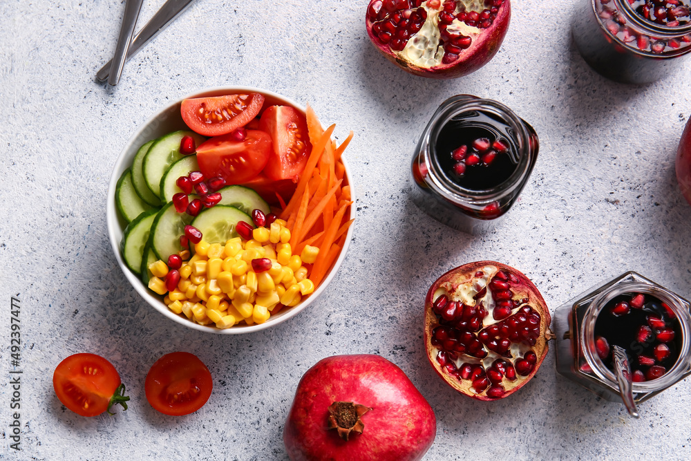 Bowl of fresh vegetable salad with pomegranate molasses on light background