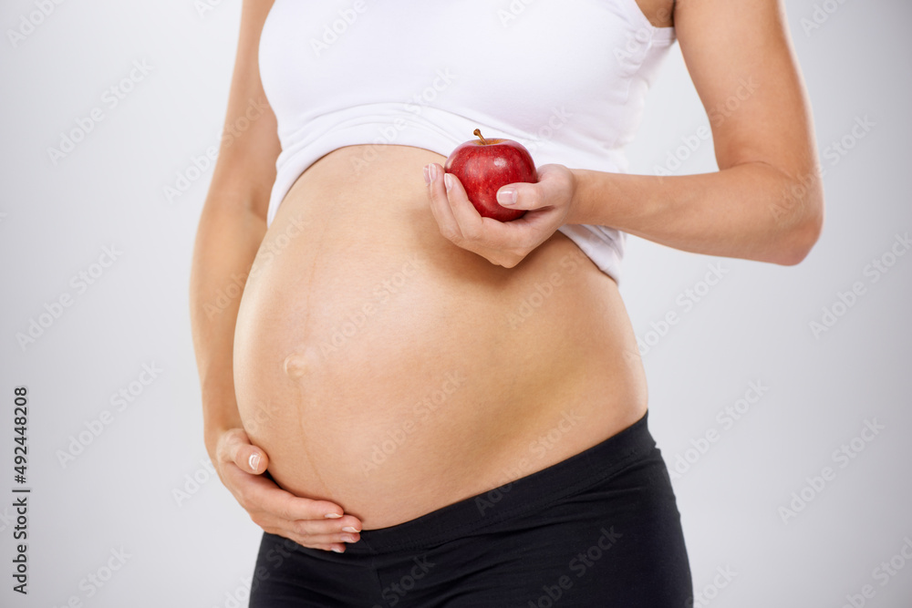 婴儿健康饮食。孕妇拿着苹果触摸造口的裁剪图