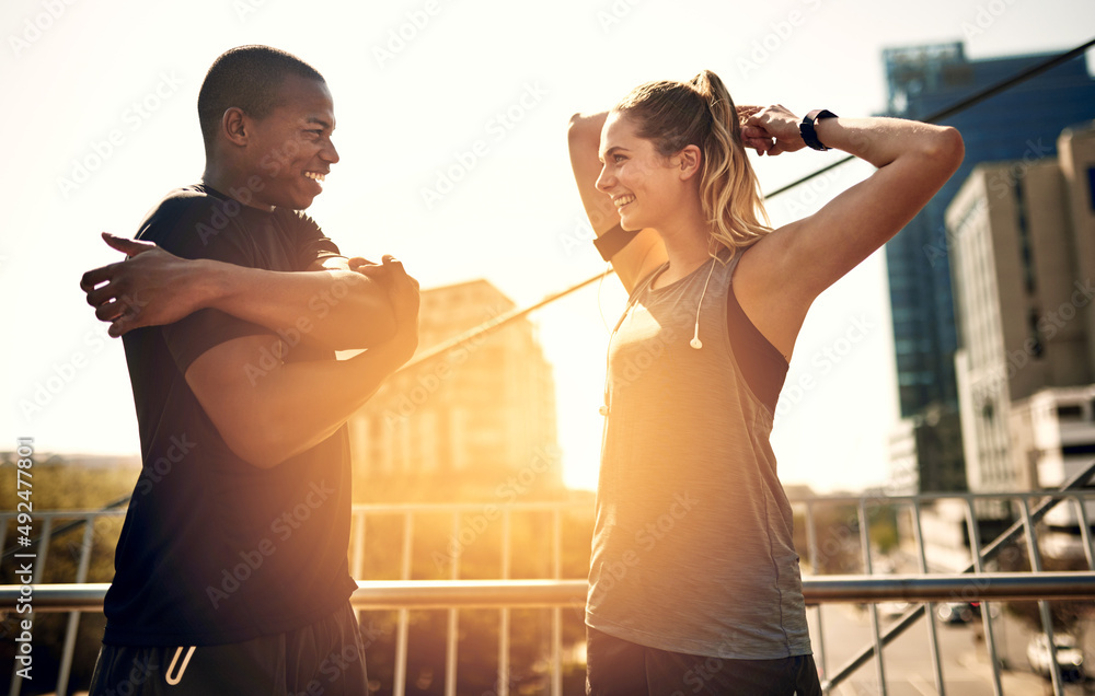 Why do it alone. Shot of two sporty young people warming up before a run.