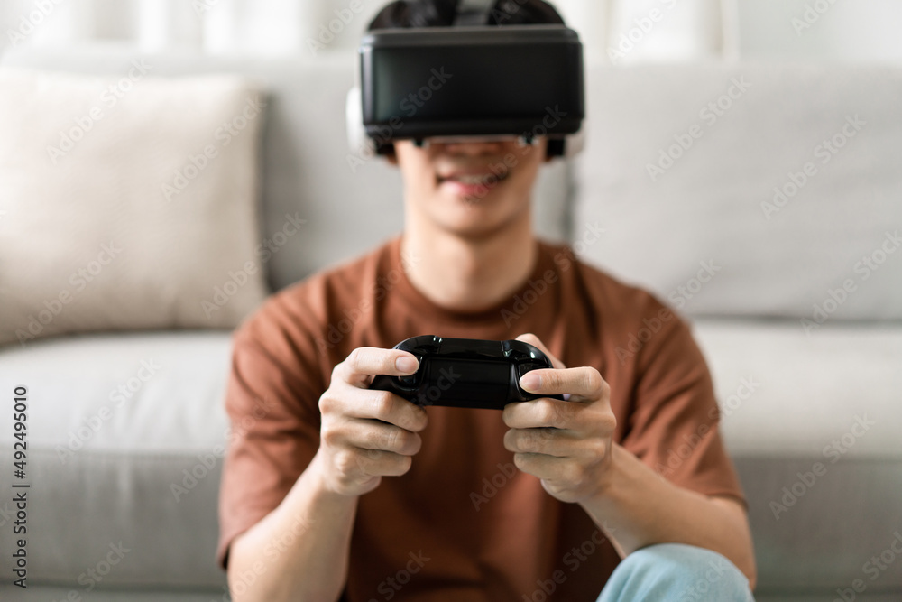 Technology Concept A man putting on a virtual reality headset and pressing a black console game whil