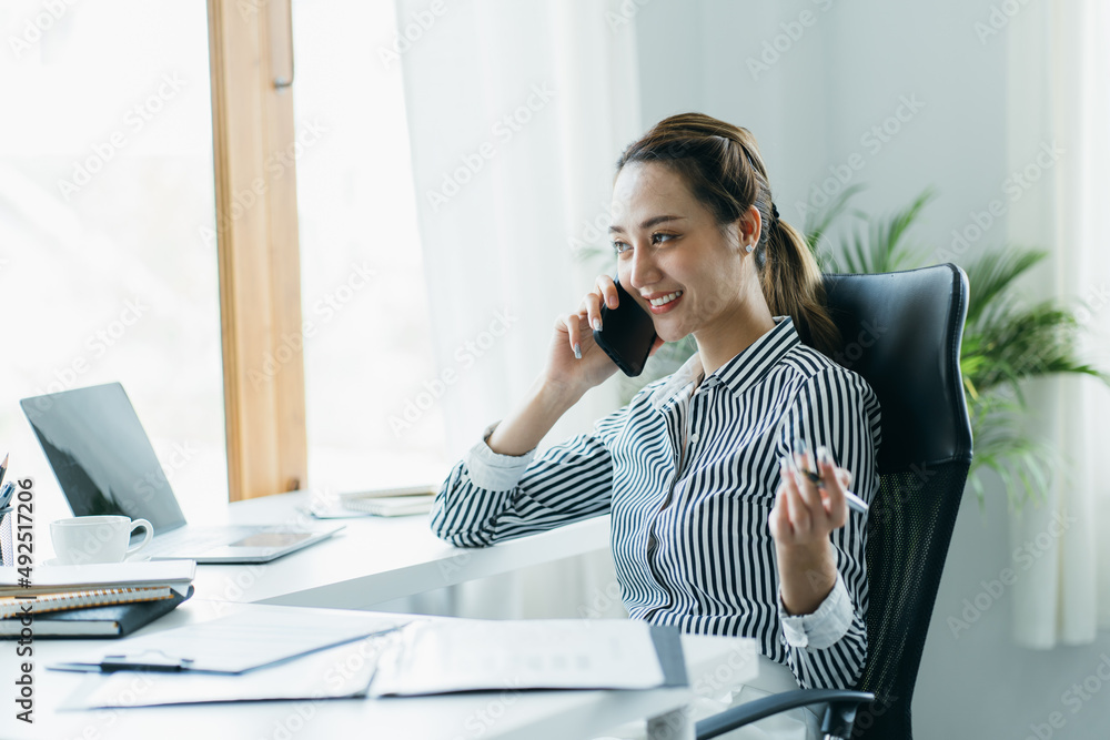 微笑的亚洲企业家女性在家庭办公室忙着用手机聊天。背景警察