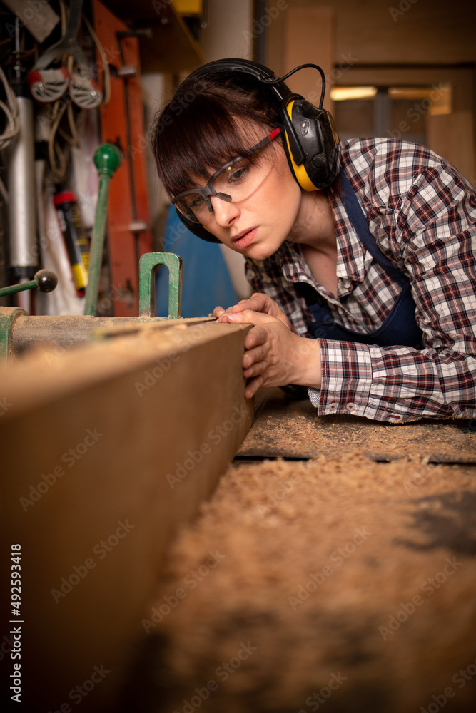 在木工车间使用工具的勤劳木工妇女