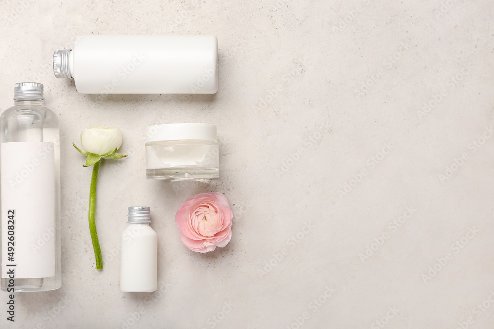 Set of cosmetic products and ranunculus flowers on light background