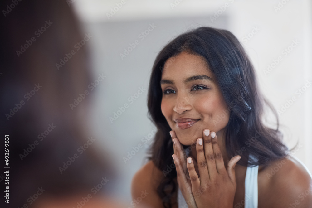 你的脸会显示出你内心的光芒。一个美丽的年轻女人在镜子里欣赏自己的照片。