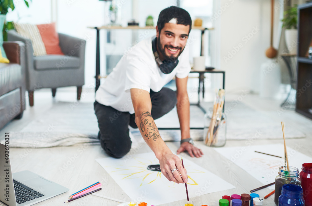 Try your hand at creating something. Shot of a young man painting while sitting on the floor at home