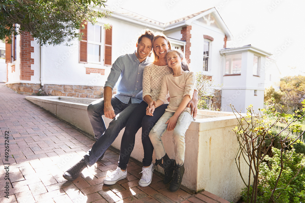 My family is my home. A portrait of a happy family sitting outside of their home.