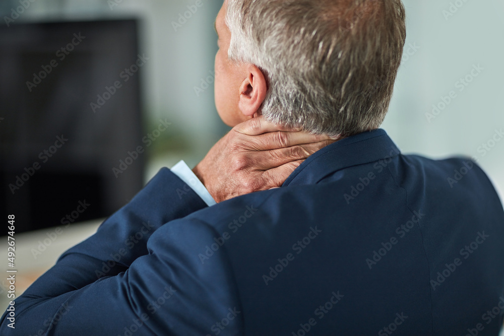 Carrying all the tension in his neck. Rearview shot of a mature businessman rubbing his neck in the 