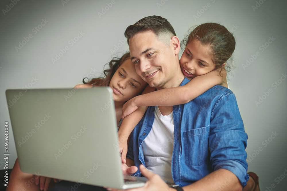 Lets video call mom. Shot of a man and his two daughters looking at something on a laptop.