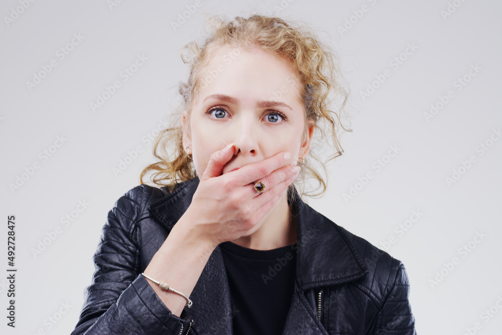 No way Tell me more. Studio shot of a young woman looking shocked against a grey background.