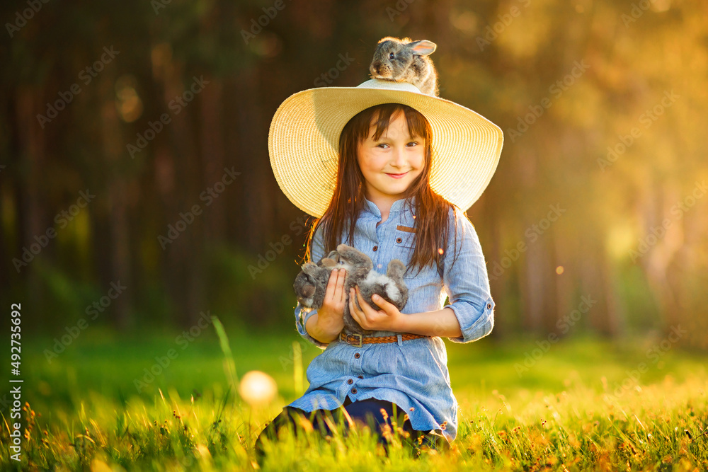 Little girl playing in the grass with rabbits.