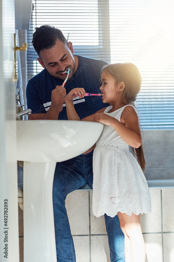 Its their daily habit. Cropped shot of a father and daughter brushing their teeth together at the ba