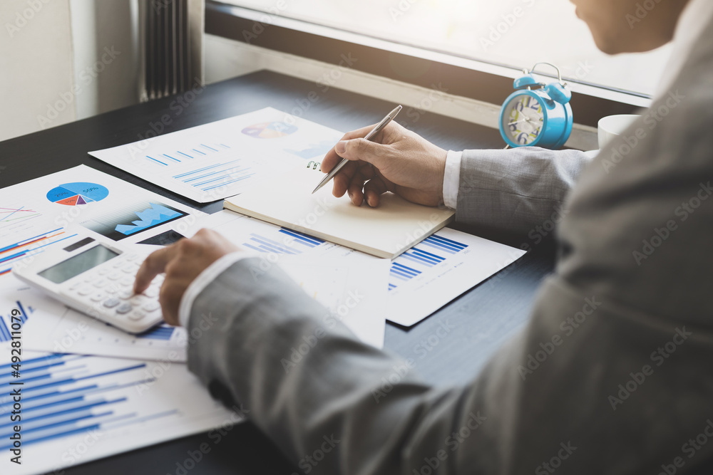 Businessman using calculator for doing math finance report on desk, tax, accounting, statistics and 