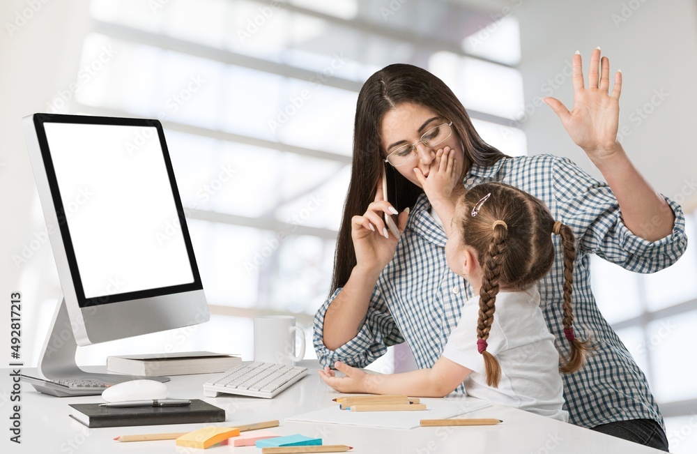 Happy busy mother working with a child on laptop