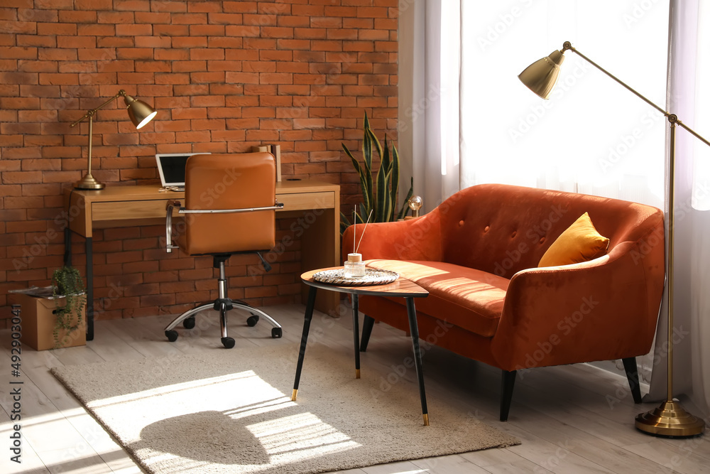 Interior of stylish living room with red sofa, workplace and golden lamps