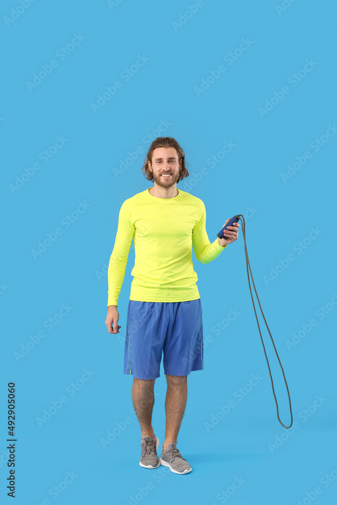 Sporty man with jumping rope on blue background