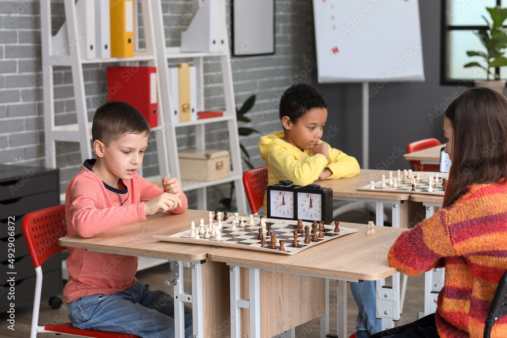 Little children playing chess during tournament in club