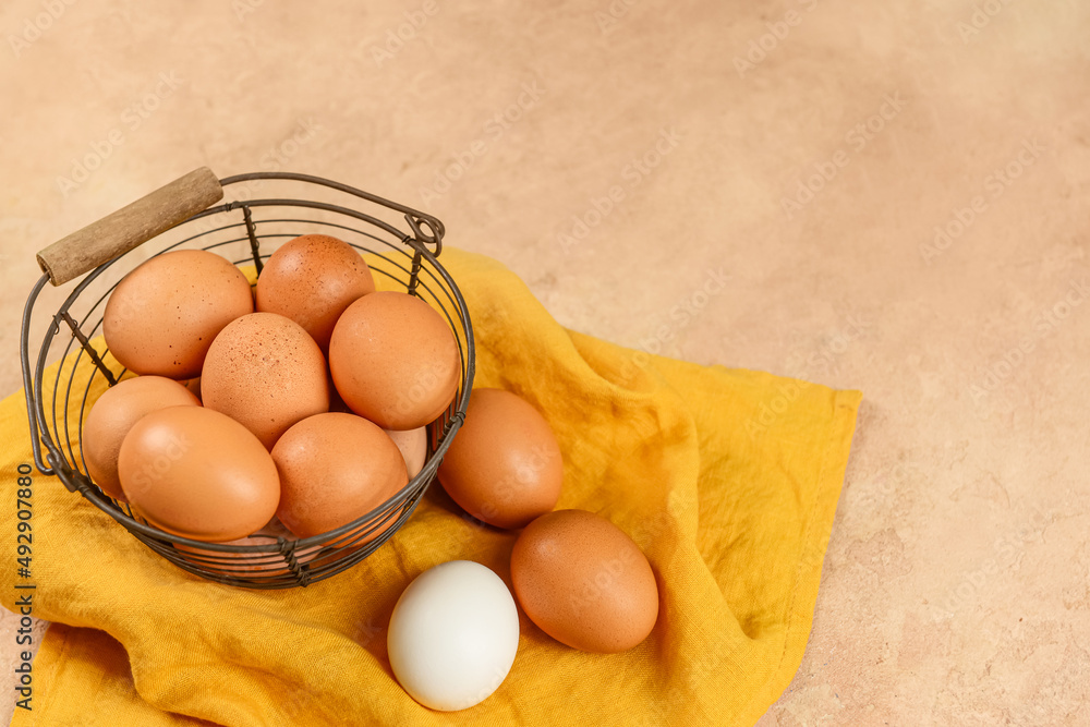 Basket with fresh chicken eggs on beige background