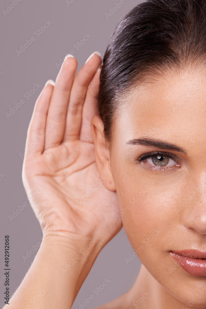 Taking your beauty advice. Beauty shot of a young woman with a cupped hand behind her ear.