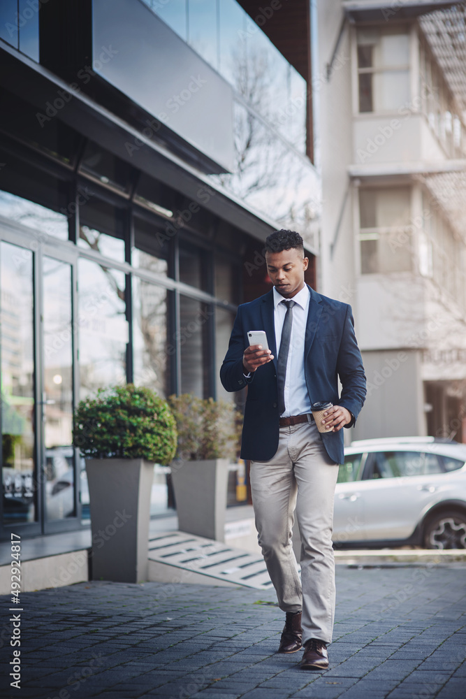 Catching a quick coffee before heading back. Shot of a handsome young businessman using a cellphone 