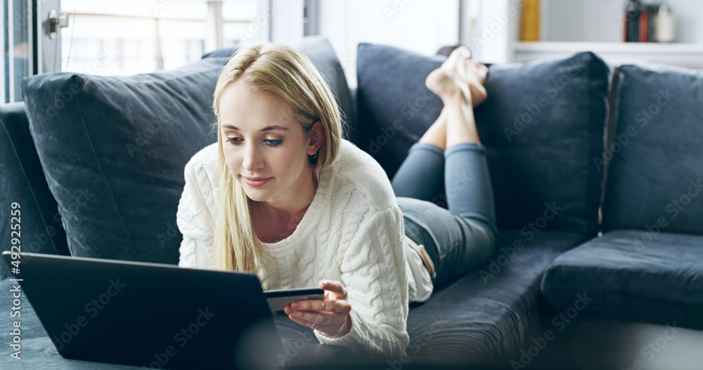 She does most of her shopping online. Full length shot of an attractive young woman using her laptop