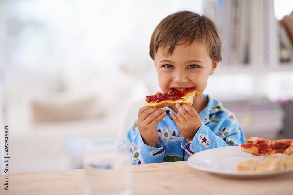 Nothing beats a good breakfast. A cute little boy eating toast with jam.