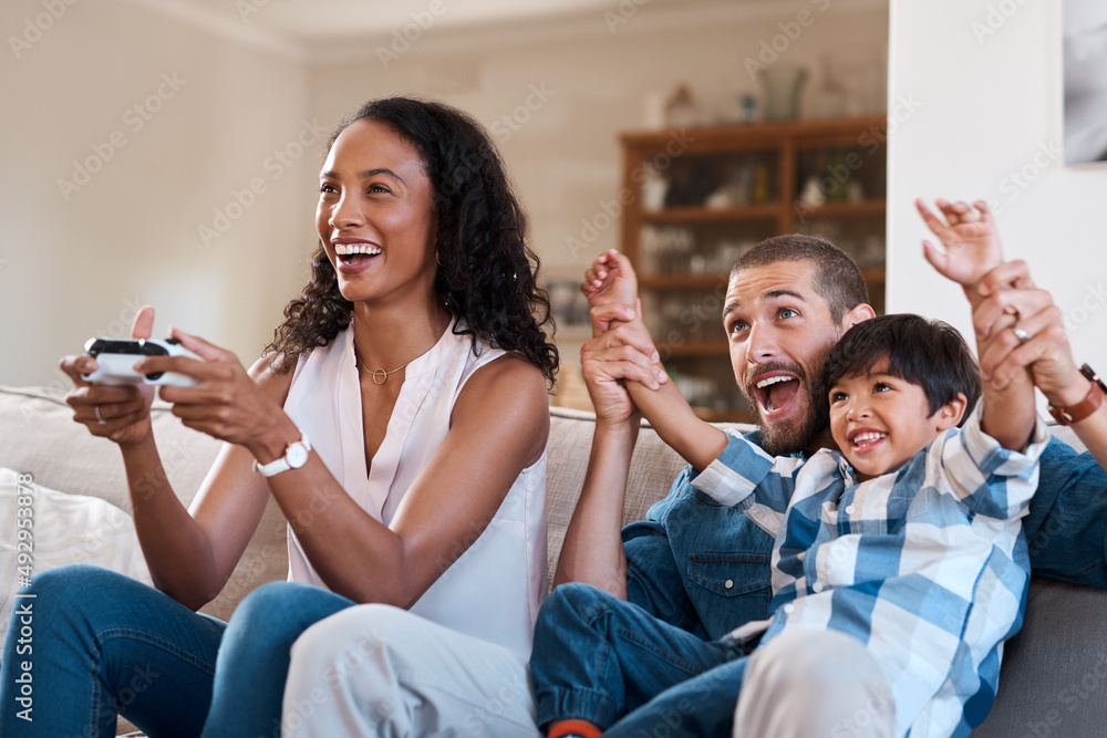 Were celebrating moms success. Shot of a woman playing video games while relaxing at home with her h