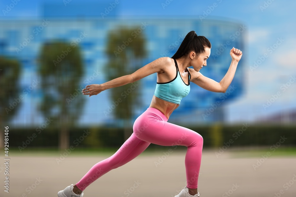 Happy fitness woman outdoors. Athletic girl wearing sportswear posing