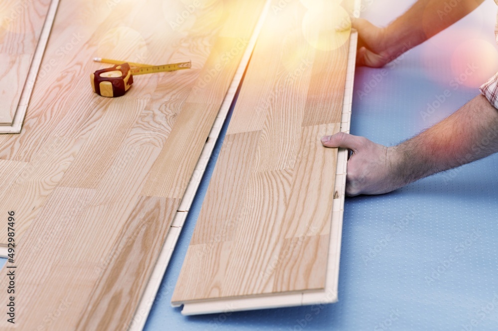 worker joining wooden floor covering at home renovation