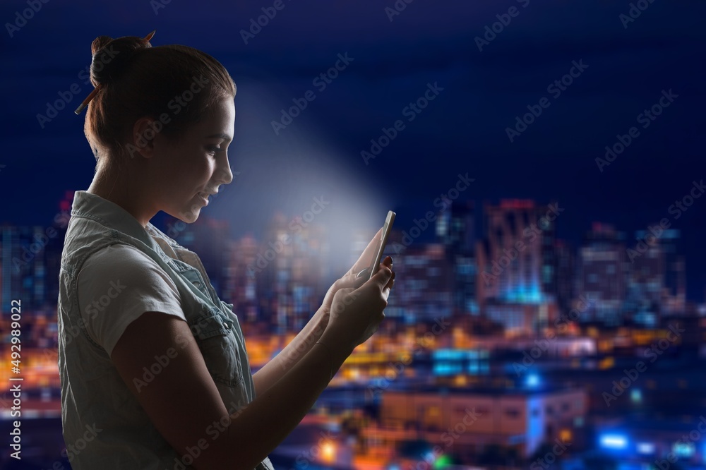 Beautiful Young Woman Using Smartphone Walking Through Night City Street background