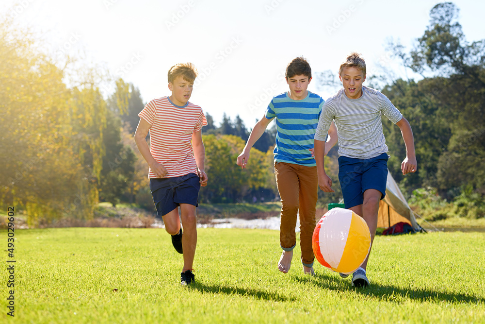 Summer memories in motion. Shot of a group of teenage boys playing with a ball outdoors.