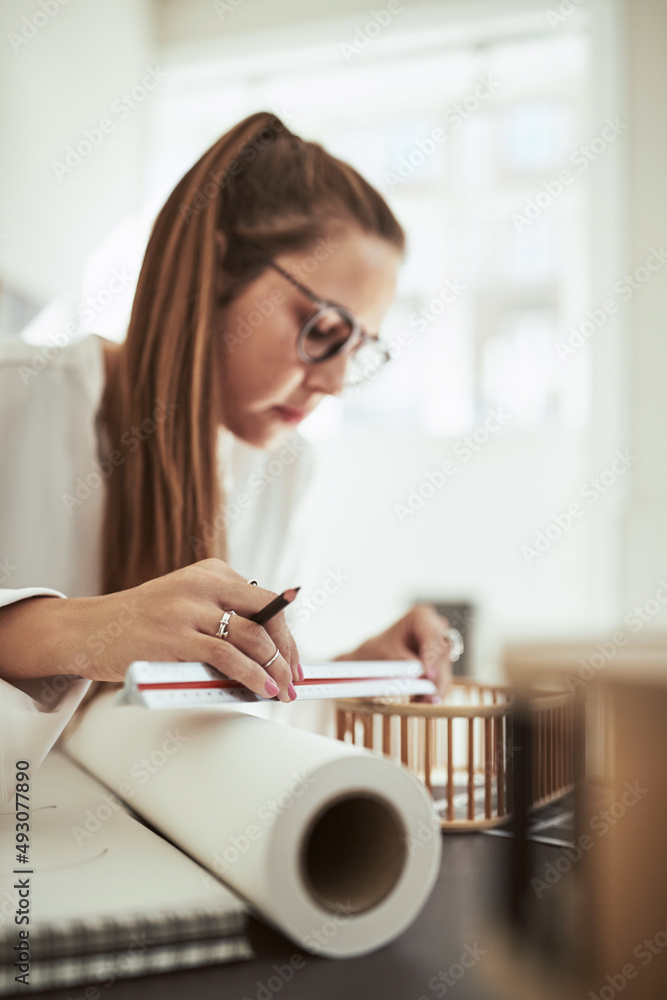 年轻的女建筑师在办公室里测量一个微型模型