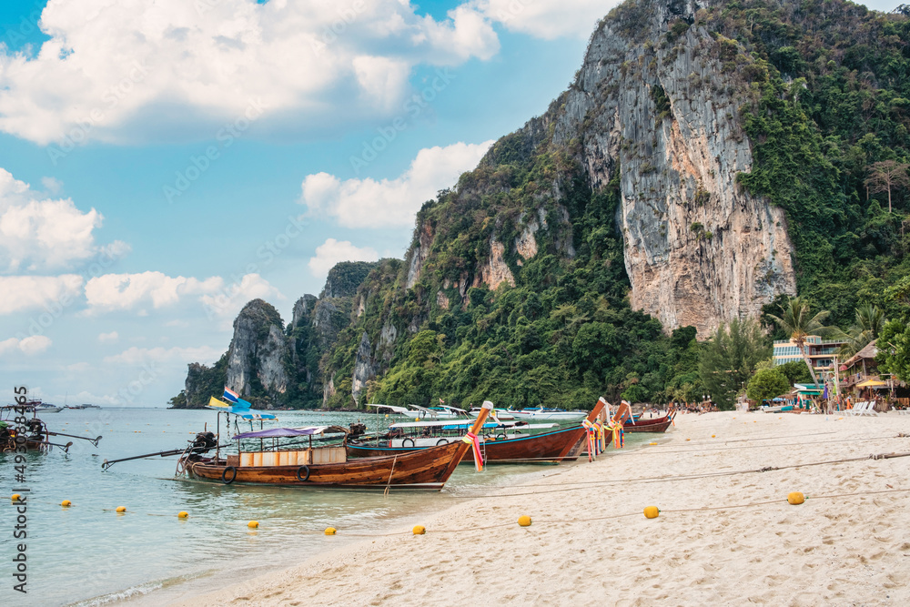 Wooden long tail boat anchored on the beach in Phi Phi island and limestone mountain on sunny day