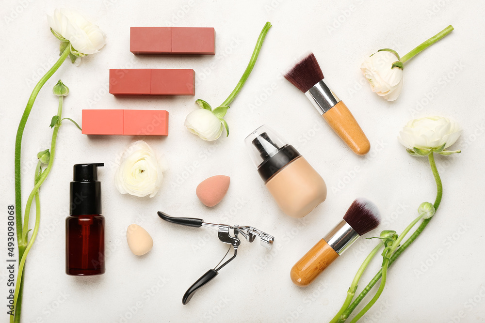 Composition with cosmetic products, supplies and ranunculus flowers on light background