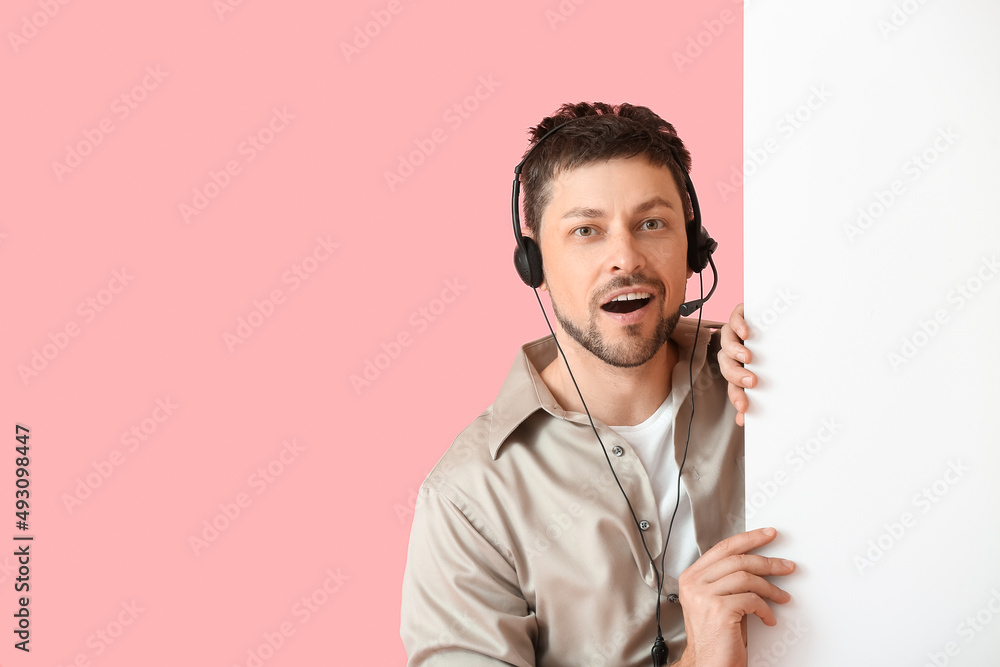 Surprised consultant of call center in headset with blank paper sheet on pink background