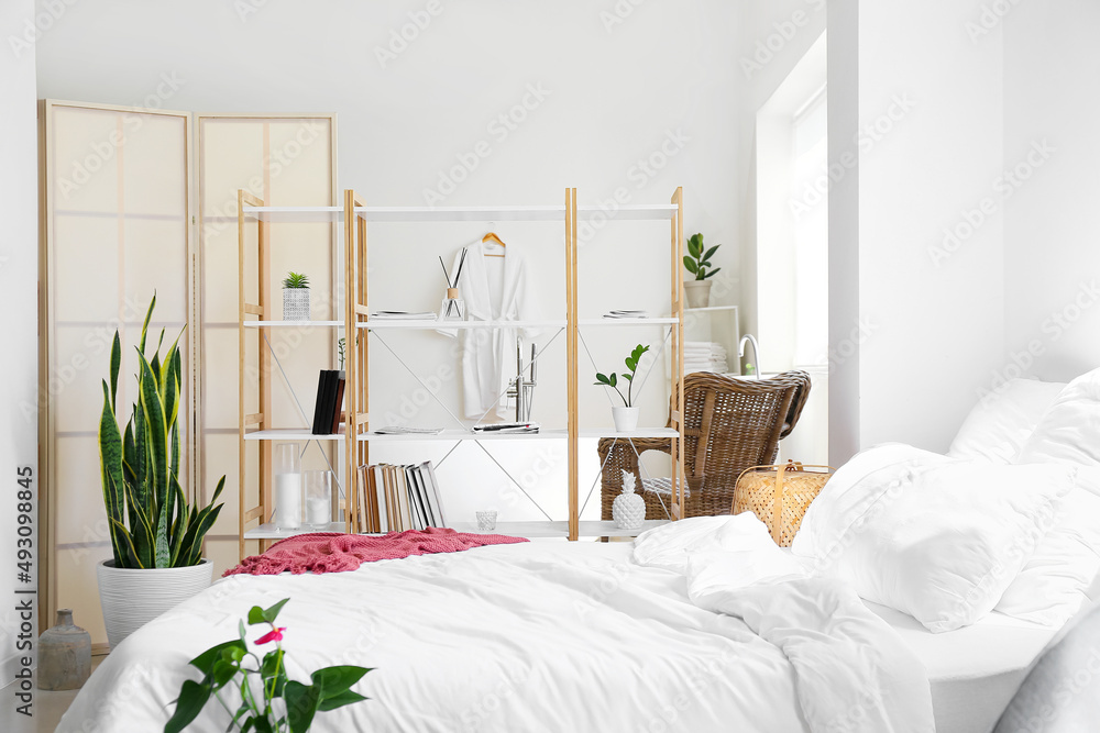 Interior of light bedroom with book shelves and bathtub