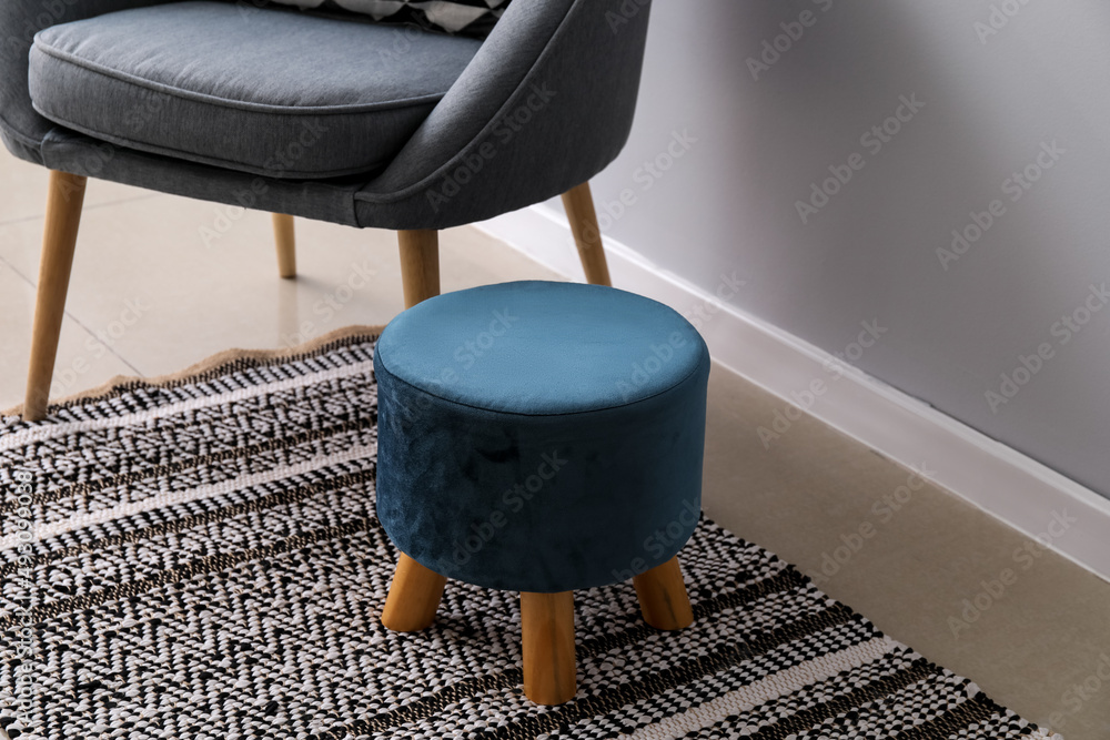 Comfortable pouf near armchair in room