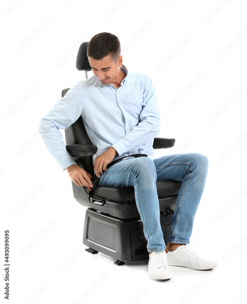 Young man fastening in car seat on white background