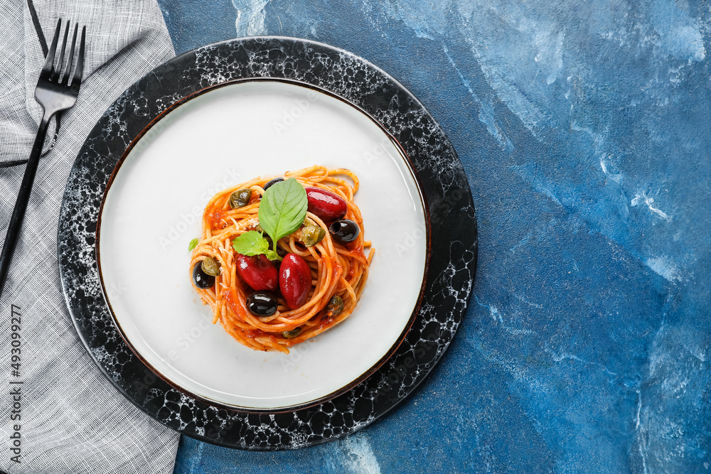 Plate with tasty Pasta Puttanesca on blue background