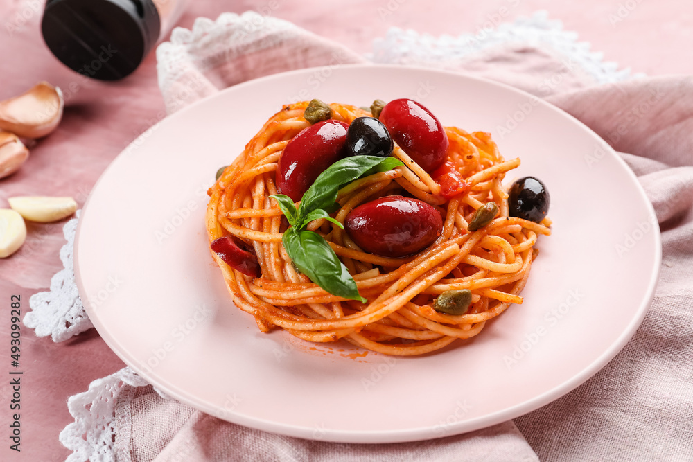 Plate with delicious Pasta Puttanesca on pink background, closeup