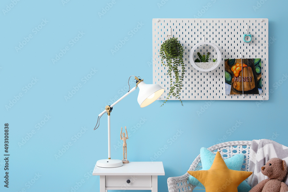 Peg board with houseplants and book hanging on blue wall in childrens room