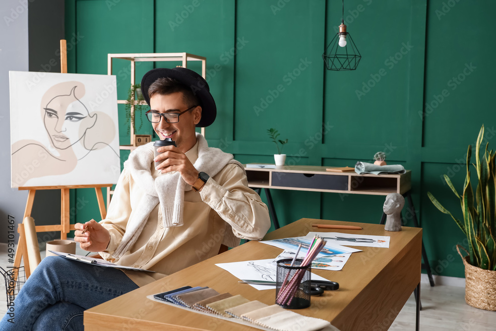 Male clothes stylist drinking coffee while working in studio