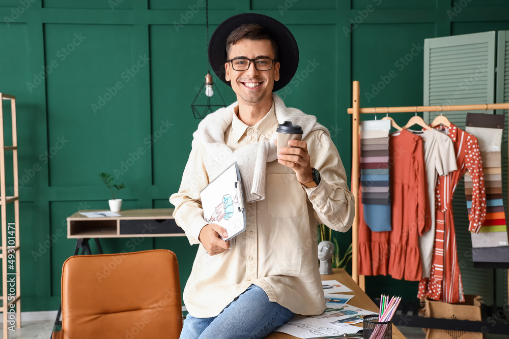 Male clothes stylist drinking coffee while working in studio