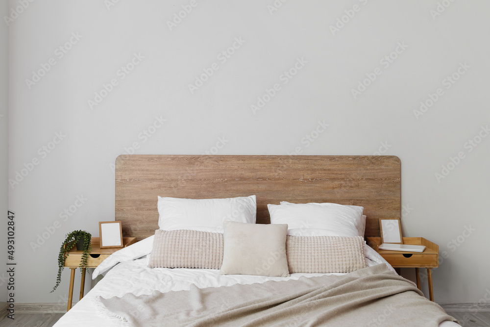 Comfortable bed and nightstands near light wall