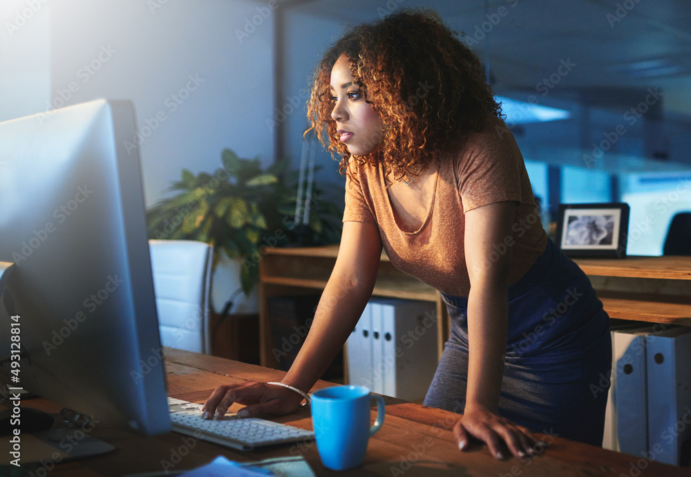 This office is open 247. Shot of a young woman working late in an empty office.